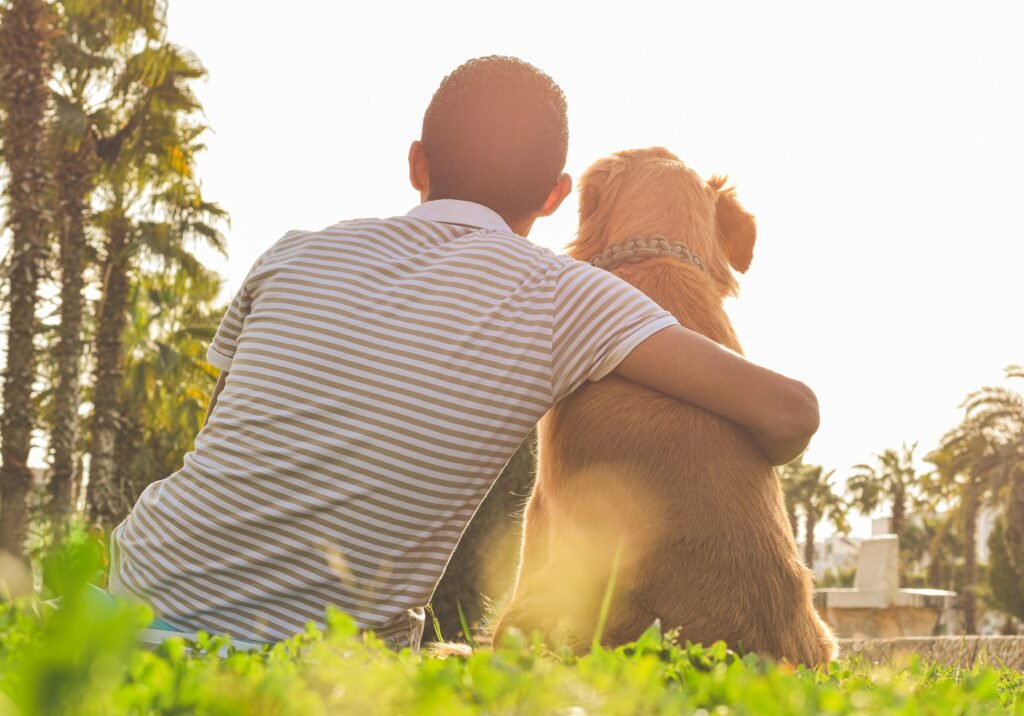 A man embraces his dog outdoors in a sunny Egyptian park, showcasing friendship.